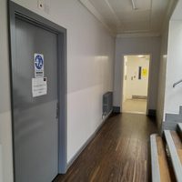 Exterior of accessible toilet from corridor with signage on grey door