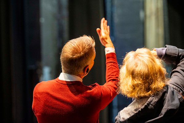 Man in red sweater holds his hand up to explain something the the woman next to him