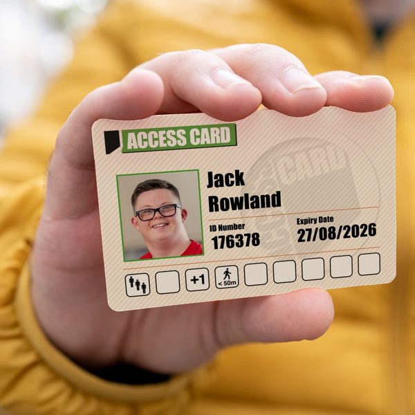 a hand holding out an Access ID Card showing a smiling male face, a customers name, ID number and Access requirement symbols