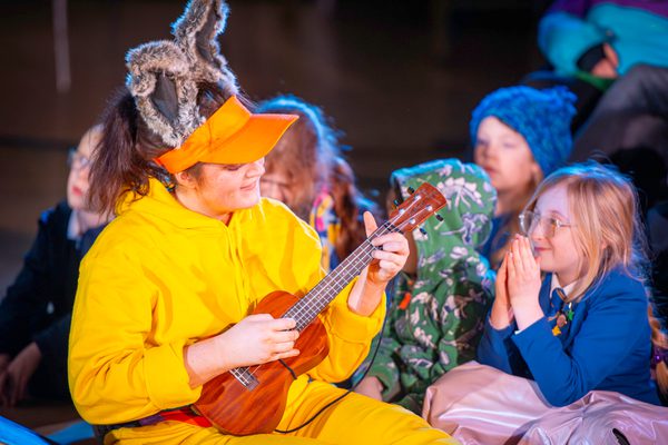 Performer playing ukulele with children in audience