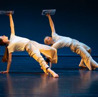 Two dancers, both with one arm on floor and one holding up image