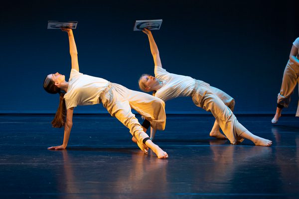 Two dancers, both with one arm on floor and one holding up image