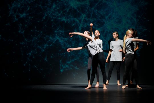 Young dancers dancing on stage with blue lights in background