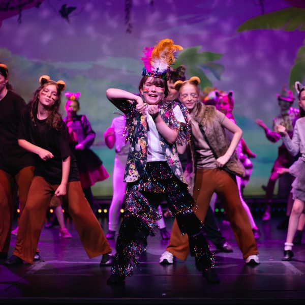 Young performers in glittery costumes dancing on stage