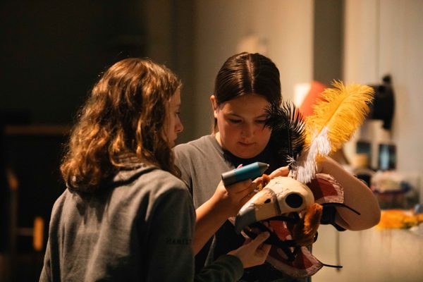 Two young people gluing feathers onto a decorative headdress