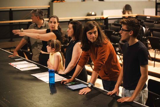 Young people and staff members watching rehearsals and offering direction