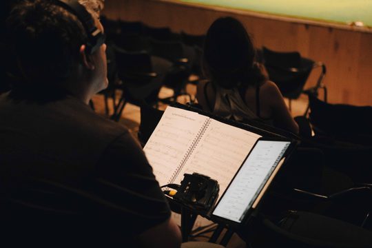 Male conductor looking at stage with sheet in front