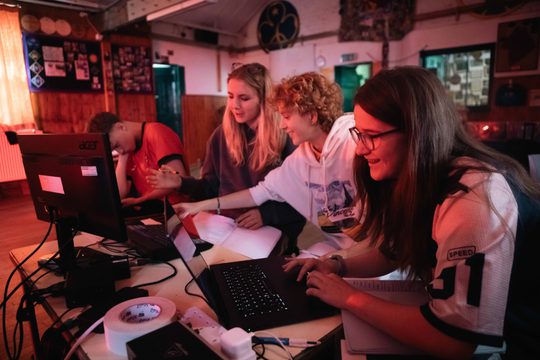 Young people working and chatting behind laptops