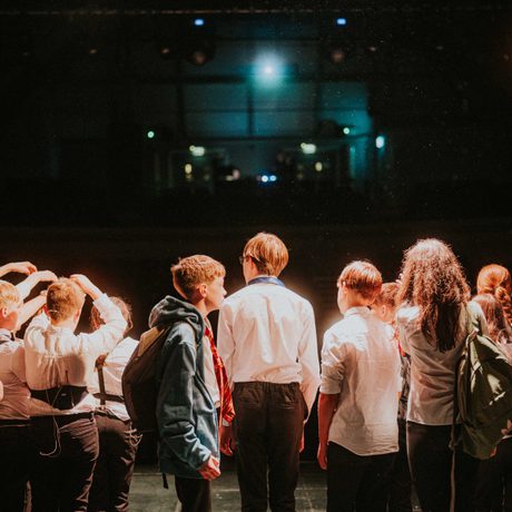 Young people performing on stage, taken from back of stage facing audience