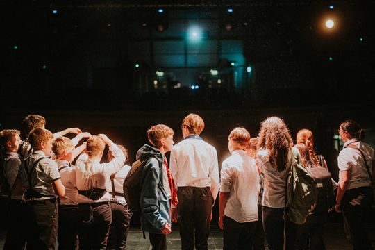 Young people performing on stage, taken from back of stage facing audience