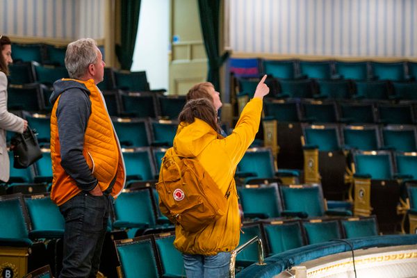 Adults on tour looking around the theatre, pointing up to features
