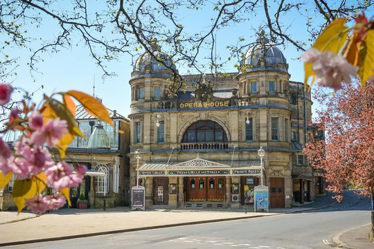 Buxton Opera House in summer with trees and flowers at the forefront