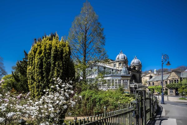 Buxton opera house in spring taken through the pavilion gardens surrounded by trees and greenery