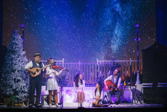 Musicians playing on a stage while snow falls on them