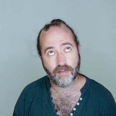 A man in a green top buttoned down half way.