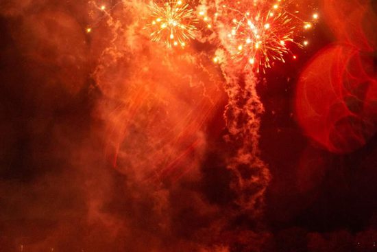 Red fireworks going off in front of a crowd.