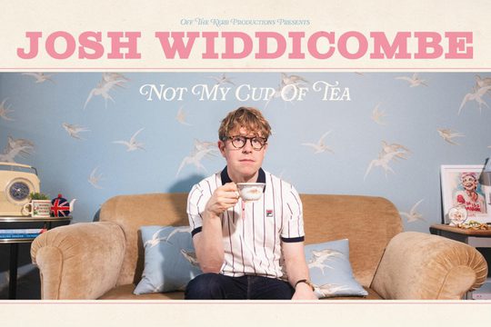 josh sat on a beige sofa drinking tea out of an ornate cup