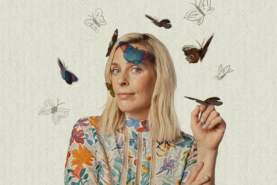 Sara in a colourful top surrounded by butterflies.