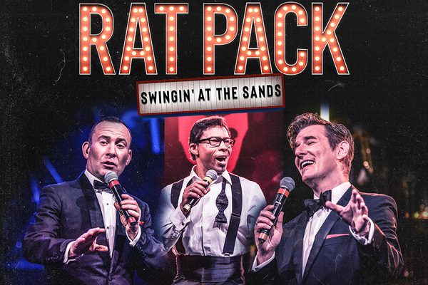Three performers in suit and tie singing into microphones next to the title