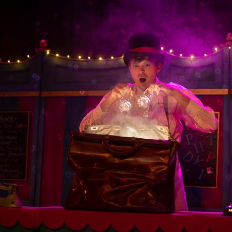A man in a top hat opening a box with light coming from it.