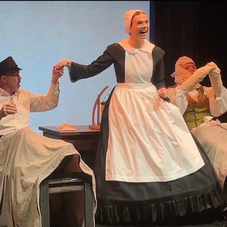 A women in a white apron holding hands with a hospital patient.