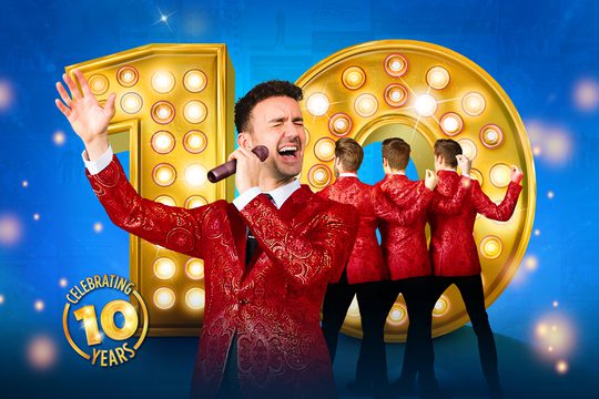 Four men in red jackets singing in front of a big yellow number 10.