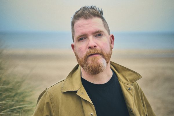 Close up of a man with a beard on the beach.
