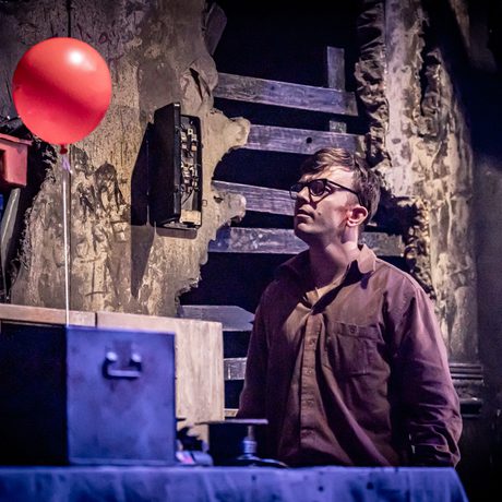 A man staring at a floating red balloon.