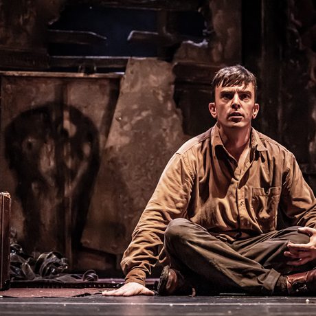 A man in brown clothes sat crossed-legged on the floor.