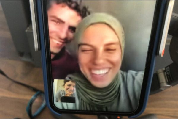 A woman on a video call with a man and a woman.