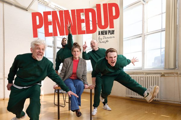 Four prisoners in green tracksuits surrounding a woman dressed smartly sat on a table