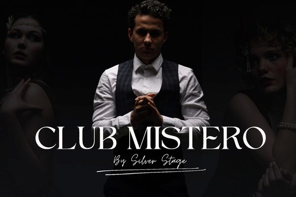 A man in a waistcoat with his hands together in front of his chest.