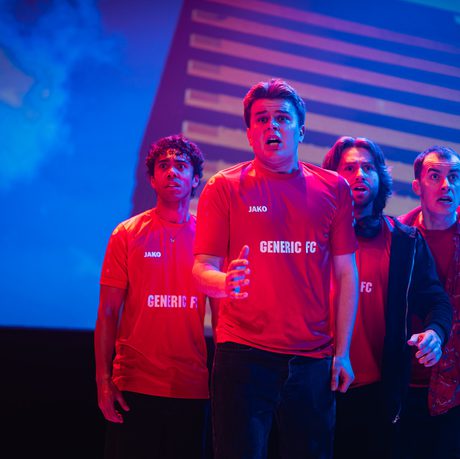 Four men in red football shirts stand in a group, looking scared.