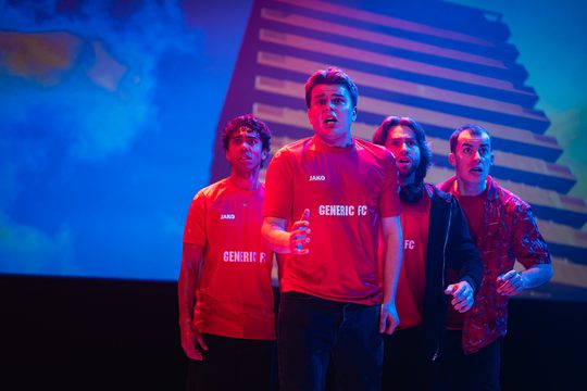 Four men in red football shirts stand in a group, looking scared.