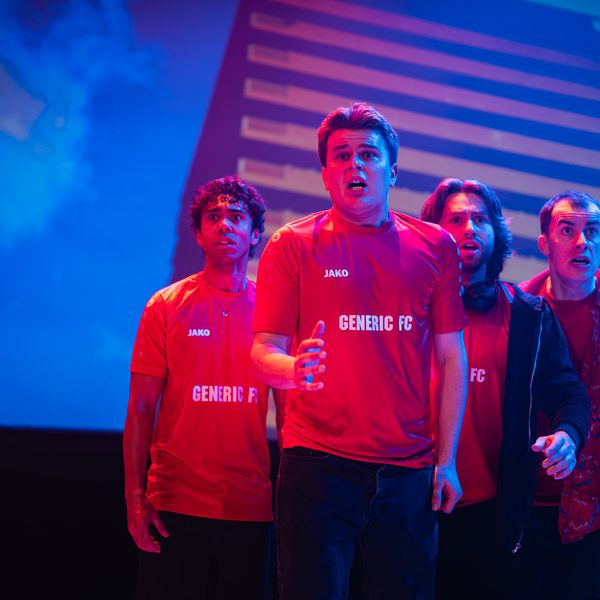 Four men in red football shirts stand in a group, looking scared.