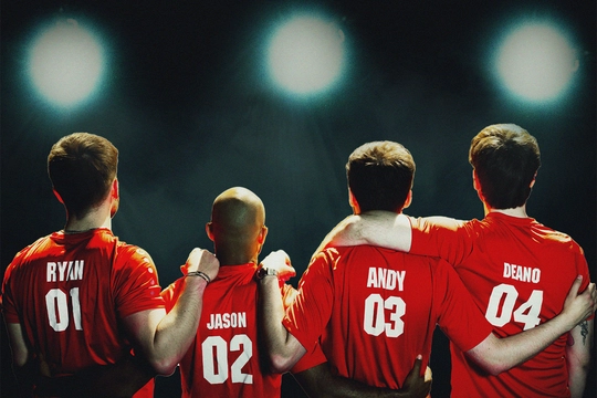 Four young men in red and white football shirts. They have their arms round each other and are facing away from the camera.