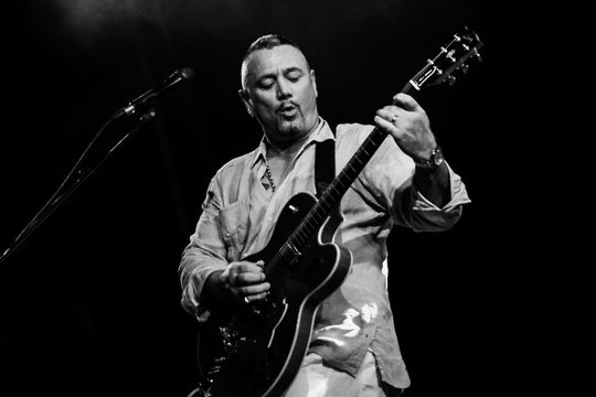 Huey Morgan in black and white, playing the guitar.