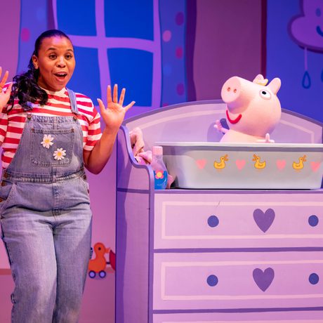A lady in blue dungarees and a red and white stripy top gives baby Evie a bath