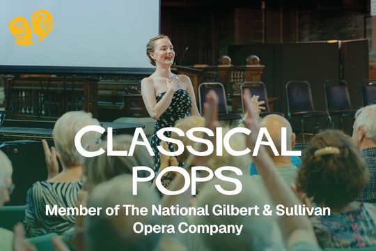 A singer in a black and white polka-dot dress smiling in front of an audience.