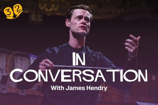 A man wearing a black shirt conducting with a baton.