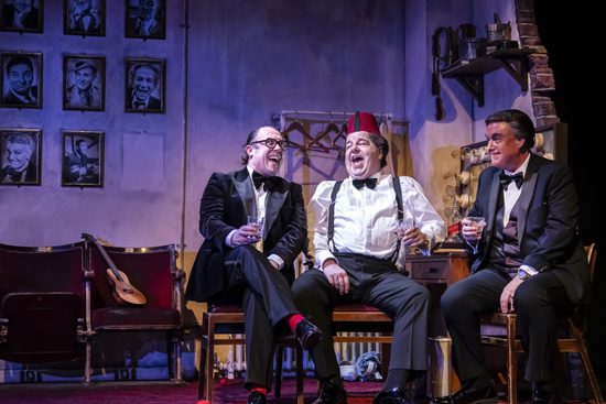 Tommy Cooper, Eric Morecambe and Bob Monkhouse sit in a dressing room, drinking whiskey and laughing.