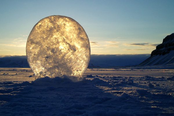 A large ball of ice in a vast snowy landscape.
