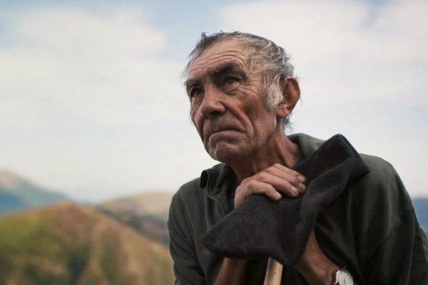 An old man walking through a beautiful landscape.