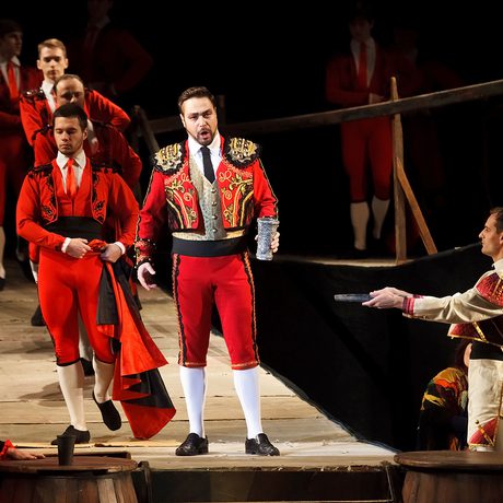 Men in red outfits walking on wooden boards.
