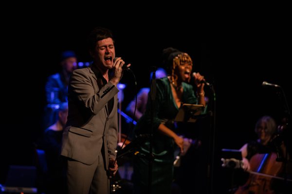 A man and a woman with their eyes closed singing into microphones.