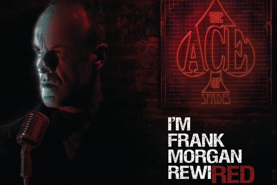 A man looking to one side with a serious expression, next to a red sign that says "The Ace of Spaces".