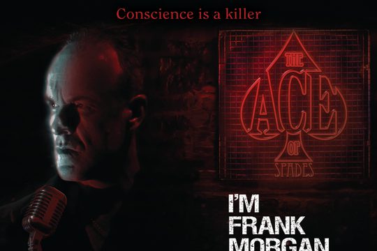 A man looking to one side with a serious expression, next to a red sign that says "The Ace of Spaces".