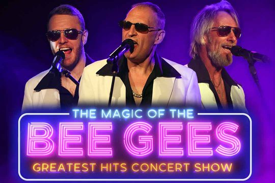 Three men in white jackets and black shirts sing into microphones.