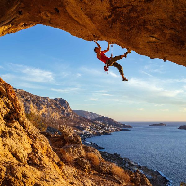 Someone climbing on a large cliff face. The sea is in the background.
