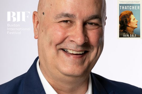 A bald man smiling at the camera against a pale, blue backdrop and a book titled 'Margaret Thatcher' by Iain Dale in the top right-hand corner.